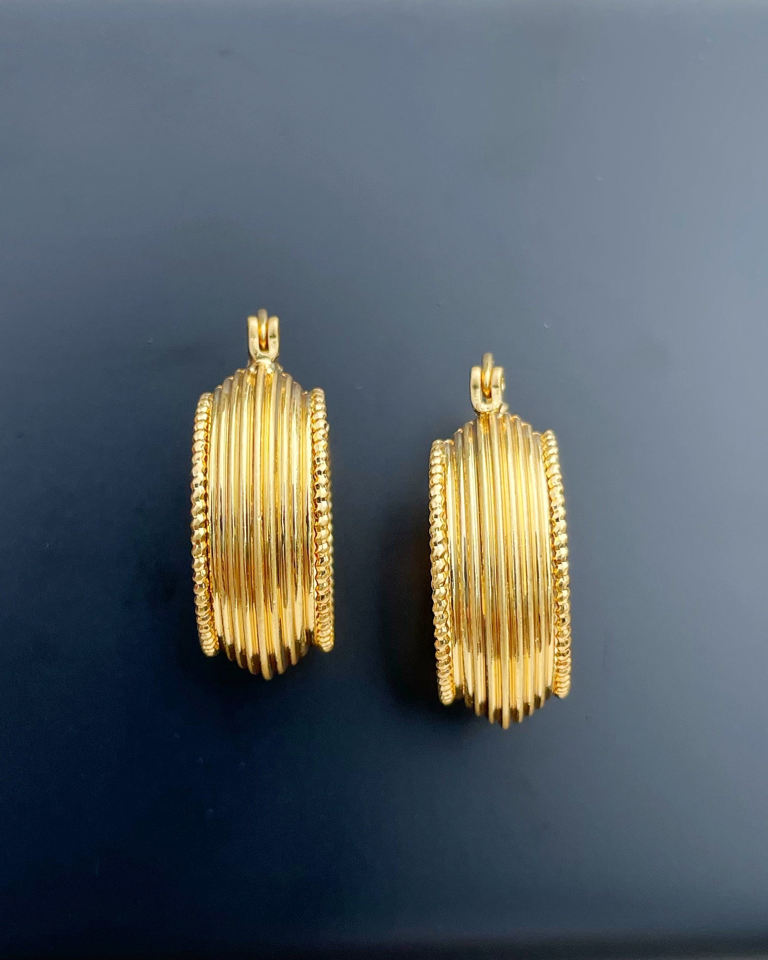 Close-up of sculptural gold hoops with ancient-inspired design