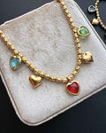 ReflA gold beaded bracelet with heart charms and colorful zircon stones. Features a lobster clasp.