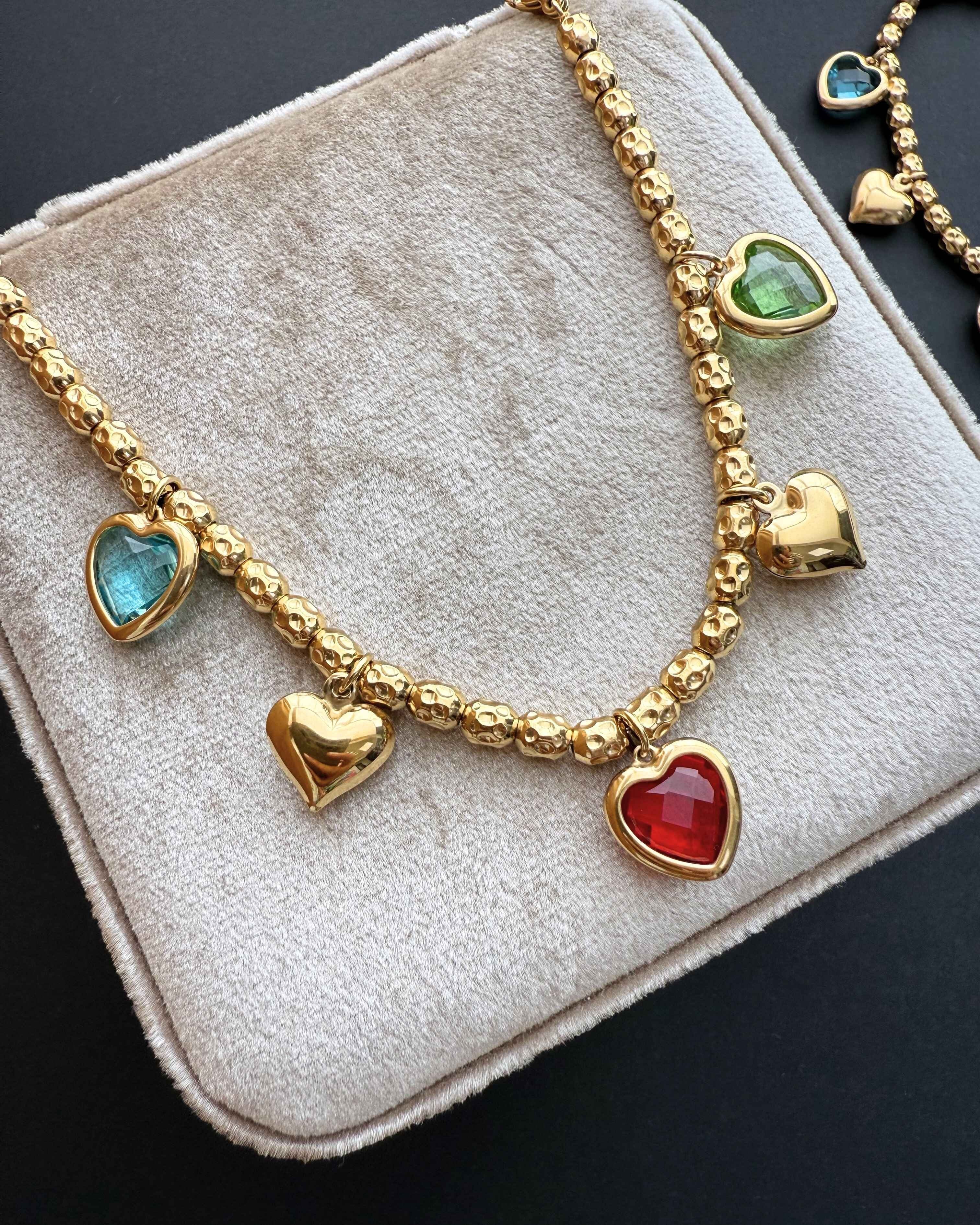 ReflA gold beaded bracelet with heart charms and colorful zircon stones. Features a lobster clasp.